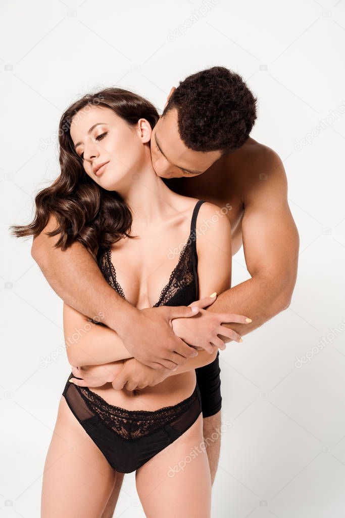 handsome mixed race man kissing neck of young woman isolated on white 