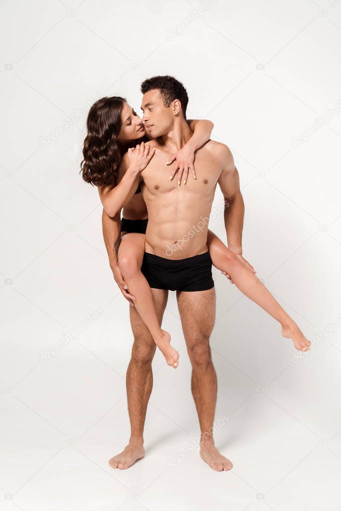 handsome muscular man piggybacking attractive sexy woman on white 