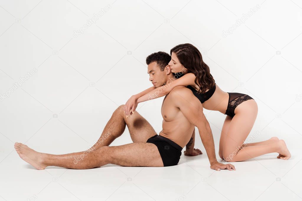 sexy woman sitting near handsome mixed race man on white 