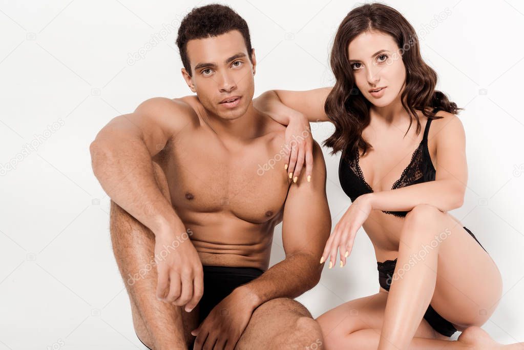 handsome mixed race man and attractive woman in underwear looking at camera on white 