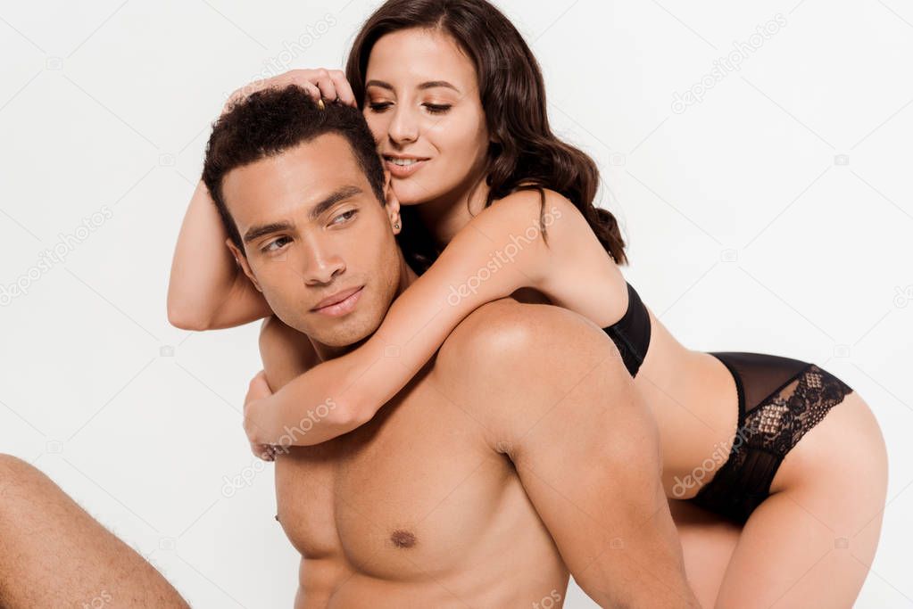 cheerful woman in underwear hugging handsome mixed race man isolated on white 