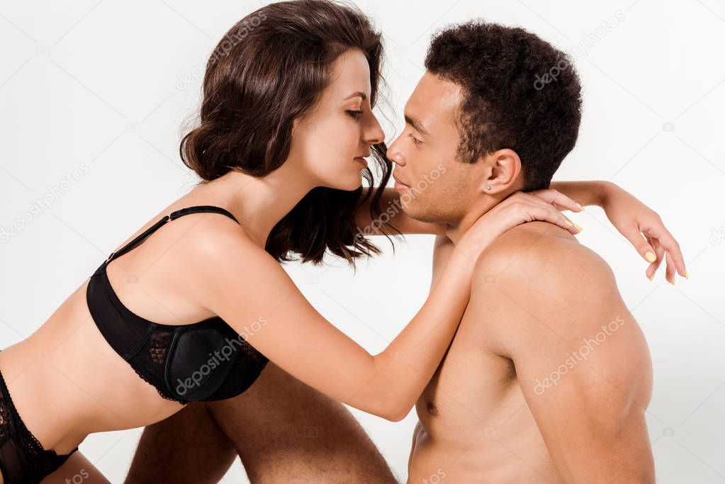 sexy woman in underwear hugging shirtless mixed race man isolated on white 