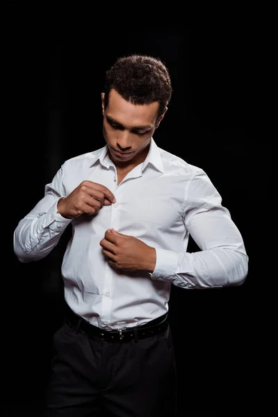 Красивый Двурасовый Мужчина Трогает Смотрит Белую Рубашку Изолированную Черном — стоковое фото