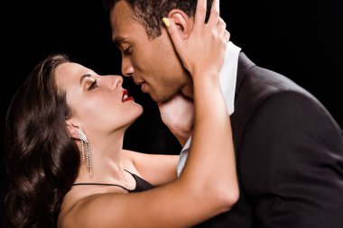 Genç kadın sarılmak ve siyah üzerinde izole yakışıklı karışık yarış adam bakıyor 