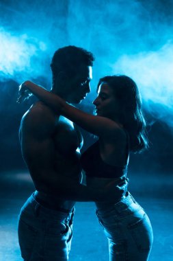 sutyen genç çekici kadın yan görünümü duman ile mavi üzerinde kaslı karışık yarış adam sarılma 