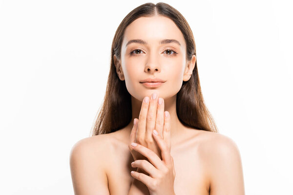 красивая молодая обнаженная женщина с идеальной кожей, смотрящая в камеру, касаясь подбородка рукой, изолированной на белом
