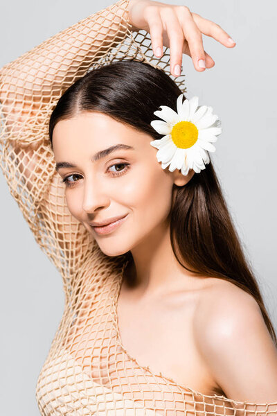 красивая улыбающаяся женщина с ромашкой в волосах, смотрящая вдаль, изолированная от серого
