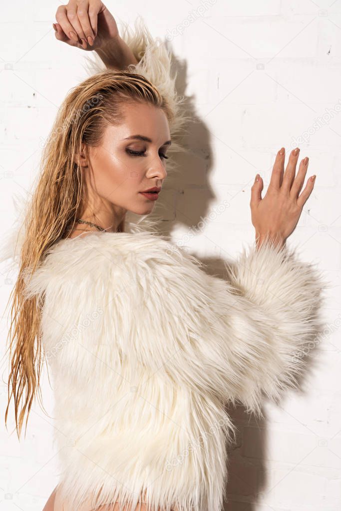 sexy girl with wet hair in white faux fur coat on white background