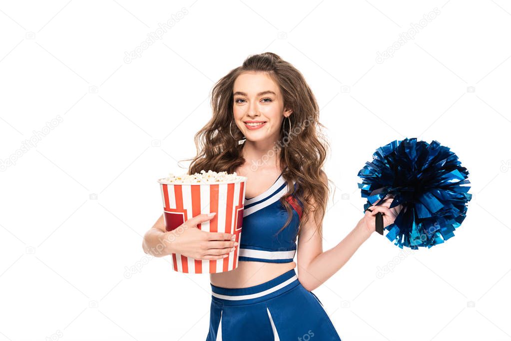 happy cheerleader girl in blue uniform with pompom and bucket of popcorn isolated on white