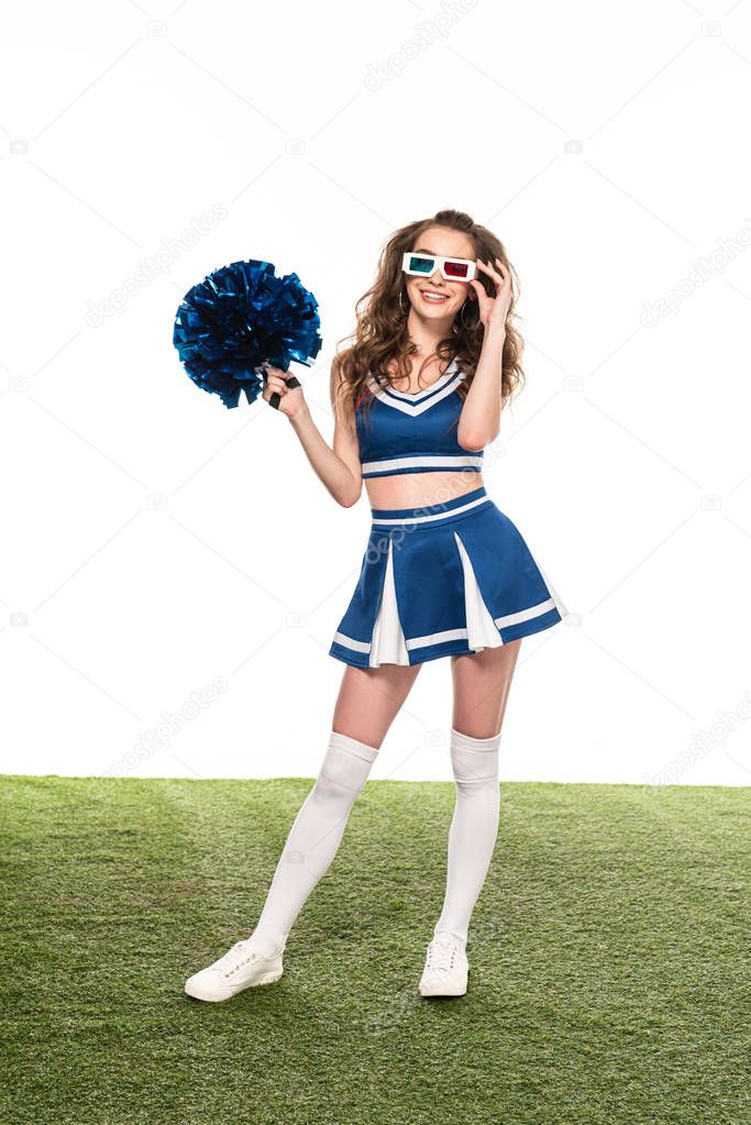 happy cheerleader girl in blue uniform and 3d glasses standing with pompom on green field isolated on white