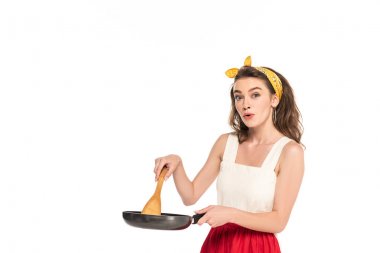 elbise ve önlük tutan tava ve ahşap spatula beyaz izole genç şok ev kadını