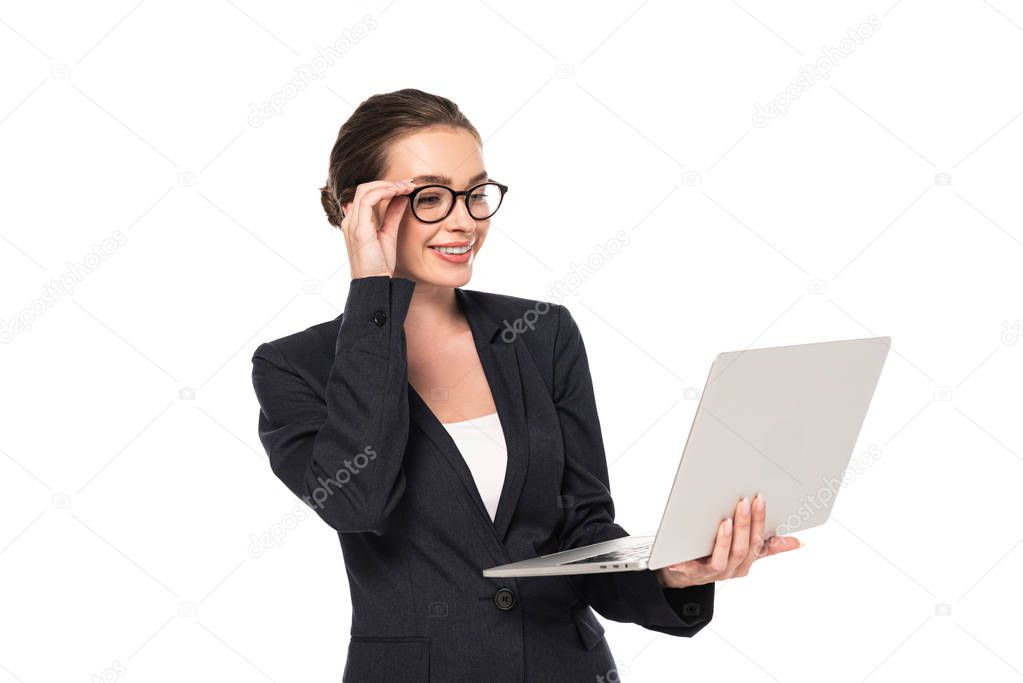 young happy businesswoman in suit and glasses holding laptop isolated on white