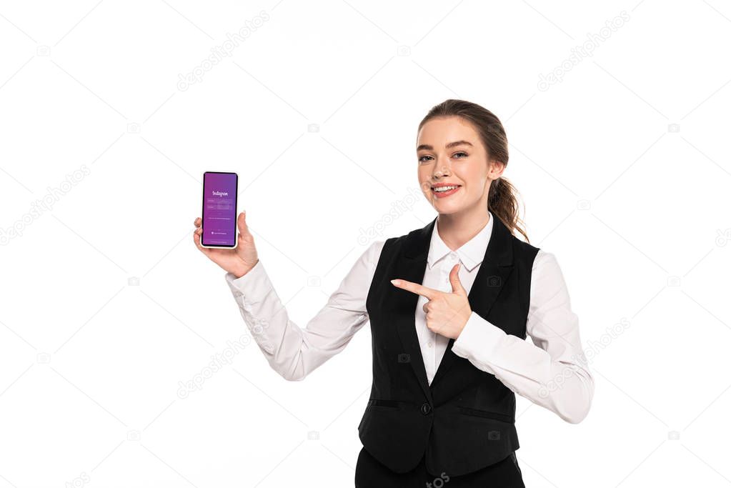 KYIV, UKRAINE - APRIL 7, 2019: happy young waitress pointing with finger at instagram app on smartphone isolated on white