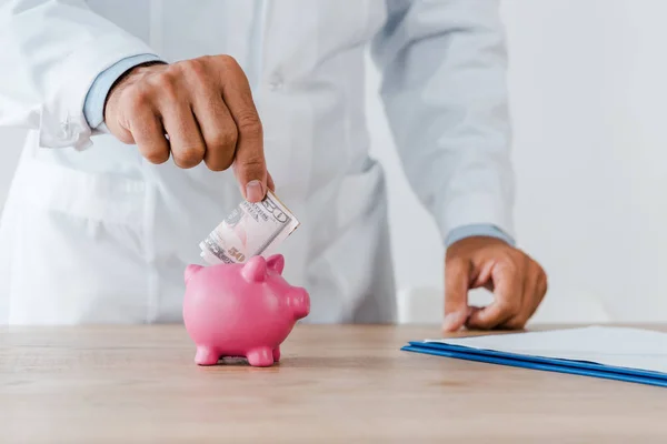 Vista Recortada Médico Casaco Branco Colocando Nota Dólar Banco Porquinho — Fotografia de Stock