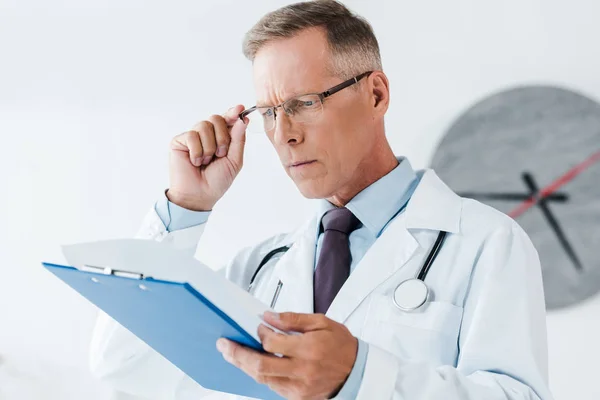 Selective Focus Handsome Doctor White Coat Looking Clipboard Touching Glasses — Stock Photo, Image