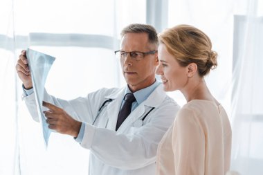 Doktor beyaz ceket içinde parmak ile işaret x-ray yakın pozitif kadın klinikte 