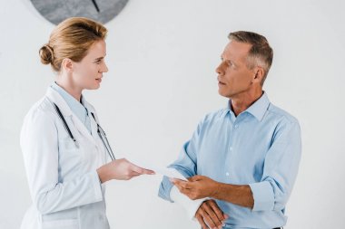 klinik adam kırık kolunda parmak ile işaret çekici doktor 