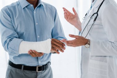 Klinikte kırık kol ile adam yakın doktor işaret görünümü kırpılmış 