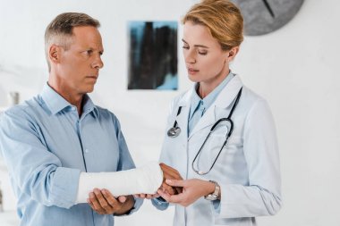 çekici doktor klinikte yakışıklı adam kırık kol bakıyor 