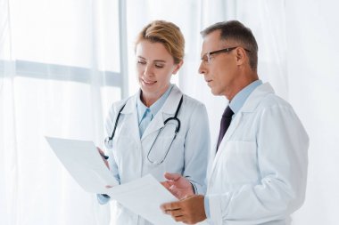 Gözlüklü yakışıklı iş arkadaşı yakın kağıt tutan neşeli doktor 
