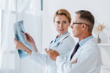 çekici Doktor tutan kalem ve x-ray yakın iş arkadaşı işaret içinde Clinic 