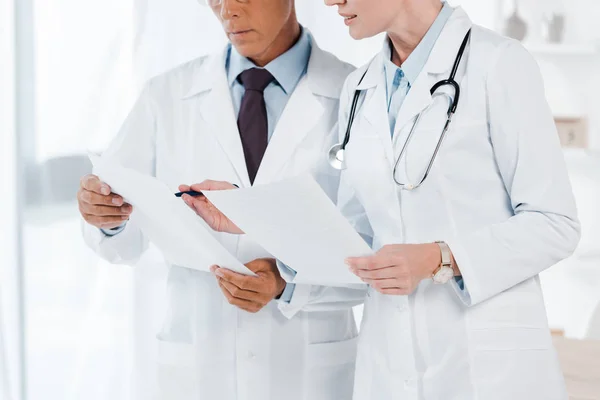 Περικομμένη Θέα Των Γιατρών Που Κατέχουν Λευκά Χαρτιά Στην Κλινική — Φωτογραφία Αρχείου