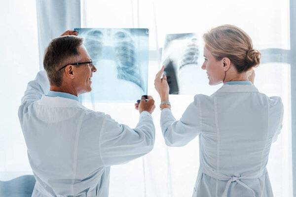 счастливый доктор в очках и красивый коллега, проводящий рентген в клинике
 