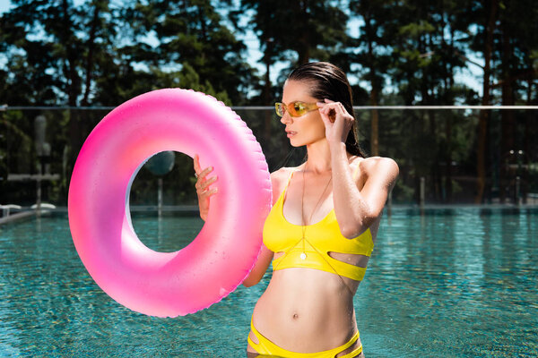 beautiful young woman posing with Swimming Ring in pool on resort