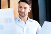 focused man looking at documents with gently smile in cafe