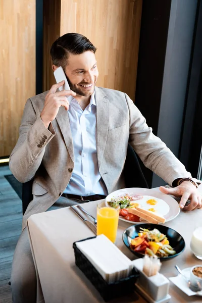 Homem Negócios Sorridente Sentado Mesa Servida Falando Smartphone Café — Fotografia de Stock
