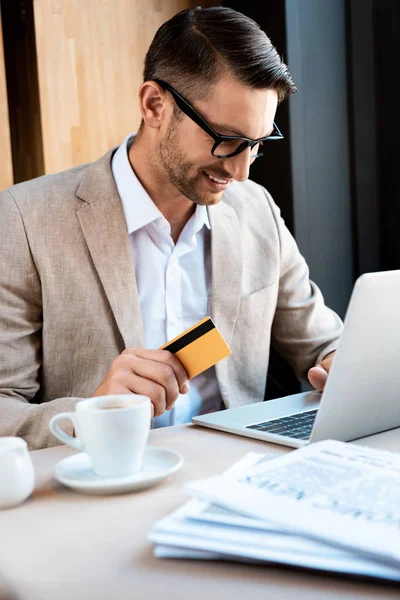 微笑的商人在咖啡馆用信用卡和笔记本电脑戴眼镜 — 图库照片