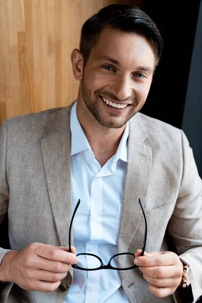 Sonriente Hombre Negocios Sosteniendo Gafas Mirando Cámara — Foto de Stock