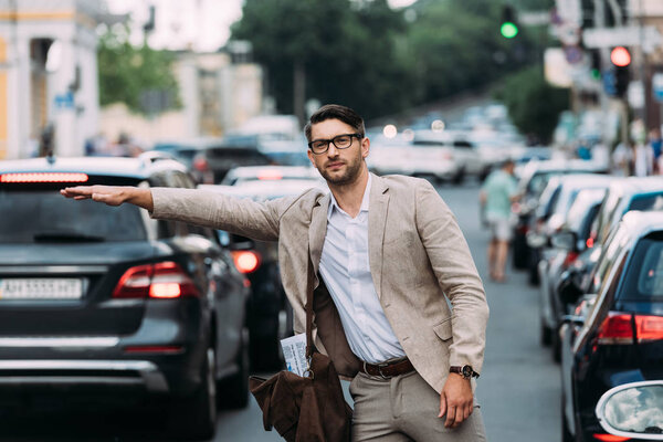 businessman in glasses with bag hitching ride on street