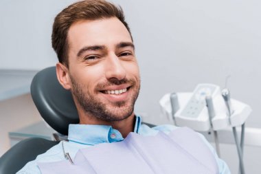 neşeli sakallı adam gülümseyen ve diş kliniğinde kamera bakıyor 