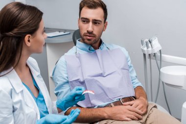 klinikte diş modeli ile diş hekimi nin yanında oturan hastanın seçici odağı 