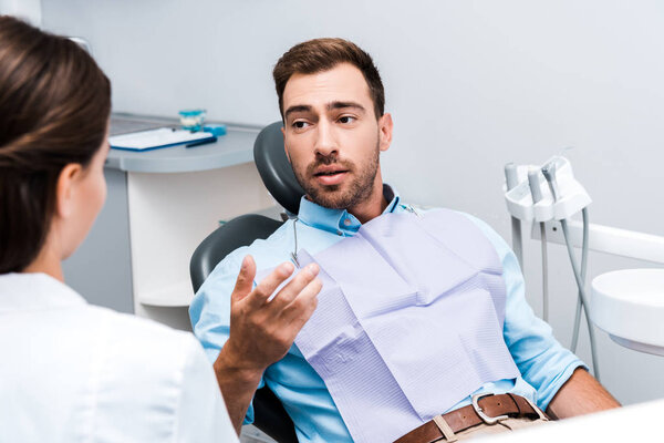 selective focus of bearded man gesturing with looking at dentist 