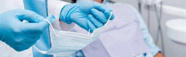panoramic shot of dentist holding medical mask in dental clinic 