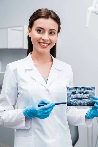 Dentista Alegre Segurando Caneta Perto Raio Sorrindo Clínica — Fotografia de Stock