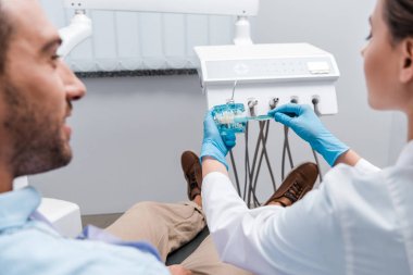 klinikte diş modeli ve adam yakınında diş fırçası tutan diş hekimi kırpılmış görünümü 