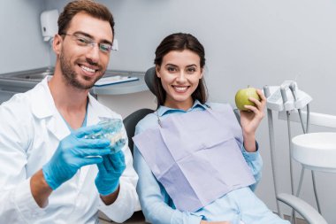 yeşil elma ile mutlu kadın yakın diş modeli tutan gözlük neşeli diş hekimi seçici odak 