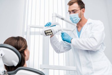tıbbi maske ve hasta yakın tıbbi lamba dokunmadan mavi lateks eldiven diş hekimi seçici odak 