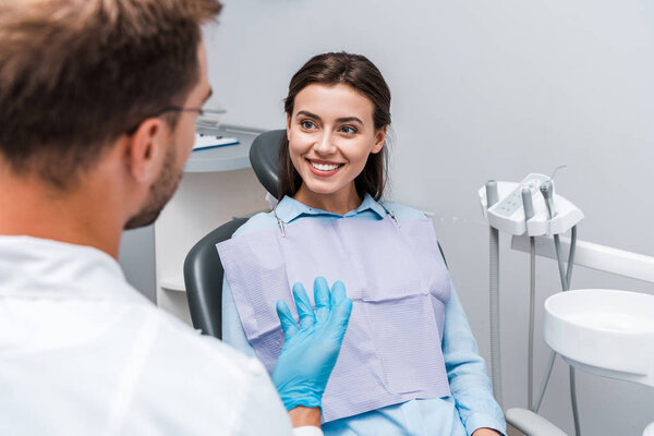 selective focus of attractive woman looking at dentist in clinic 