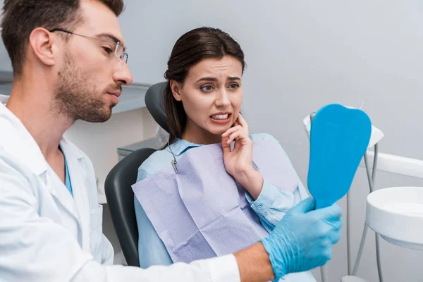 Foco Seletivo Menina Olhando Espelho Tocando Rosto Perto Dentista Bonito — Fotografia de Stock