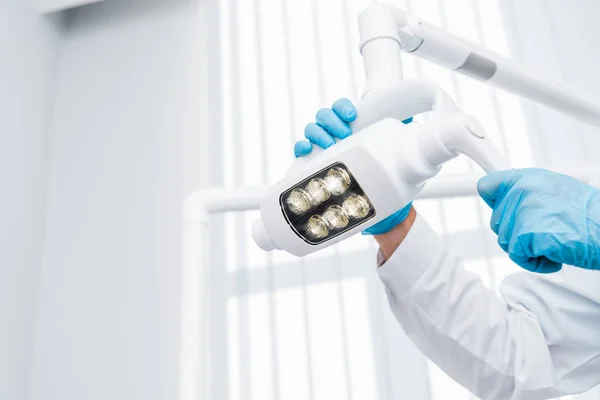 Wykadrowany Widok Dentysta Rękawice Lateksowe Dotykając Lampy Medycznej — Zdjęcie stockowe