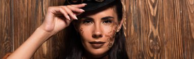 panoramic shot of attractive steampunk woman looking at camera with gently smile on wooden clipart