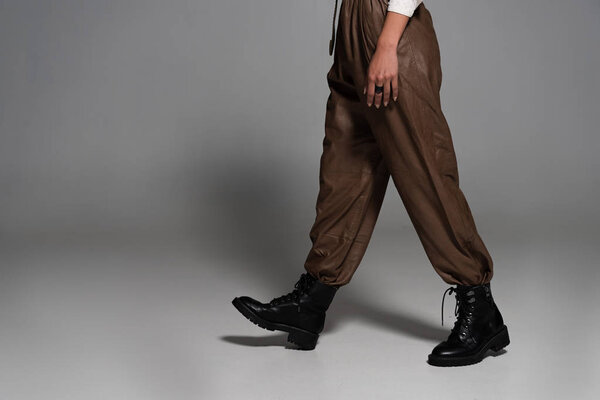 частичный вид женщины-стемпанка в черных сапогах на сером
