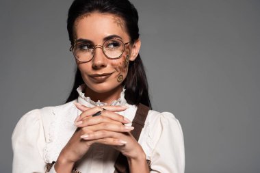 pensive steampunk kadın gri izole sıkıştırılmış elleri ile uzağa bakıyor