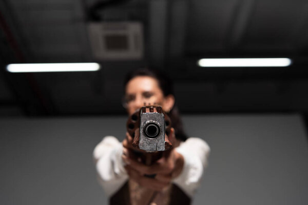 selective focus of confident steampunk woman aiming with pistol at camera