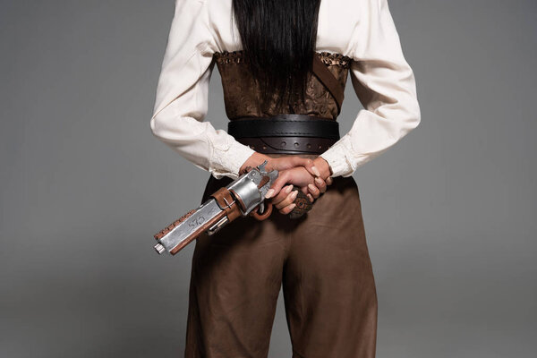 cropped view of steampunk woman holding vintage pistol on grey