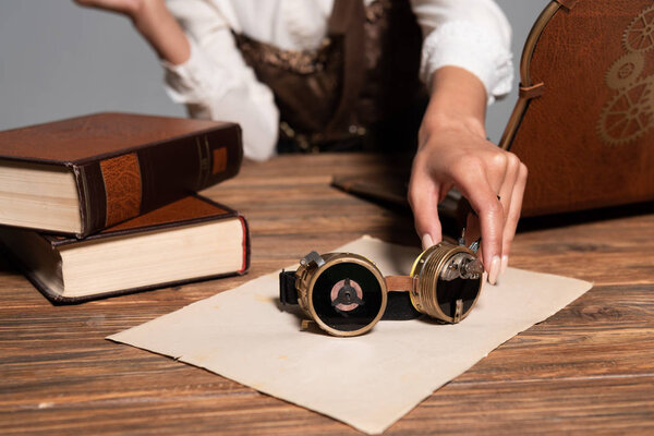 cropped view of woman holding steampunk goggles at workplace
